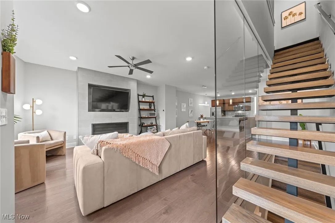Living room featuring a fireplace, wood finished floors, recessed lighting, stairs, and ceiling fan