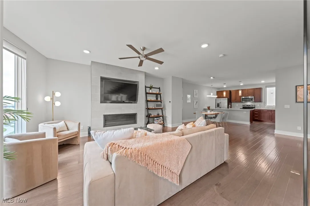 Living room with a tiled fireplace, dark wood finished floors, a ceiling fan, and recessed lighting