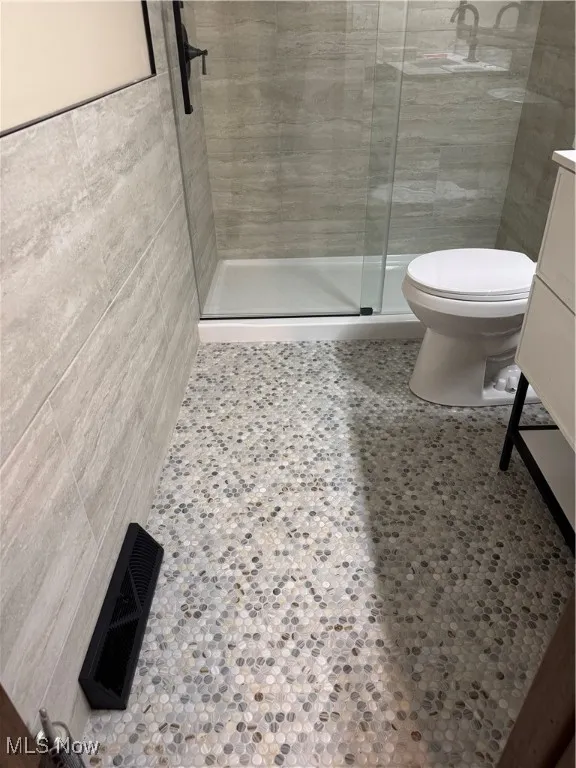 Full bathroom featuring tile walls, a shower stall, and vanity