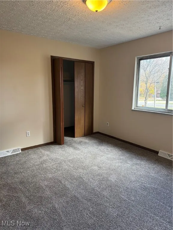 Unfurnished bedroom with carpet flooring, a closet, and a textured ceiling