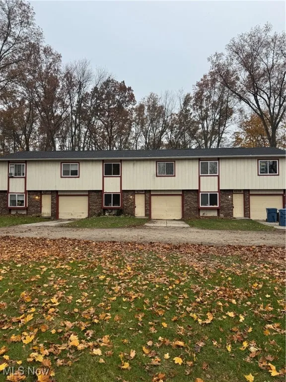 View of front of home with brick siding, driveway, and a front lawn