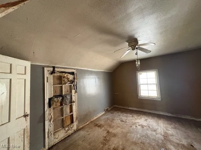 Bonus room featuring a textured ceiling, lofted ceiling, and ceiling fan