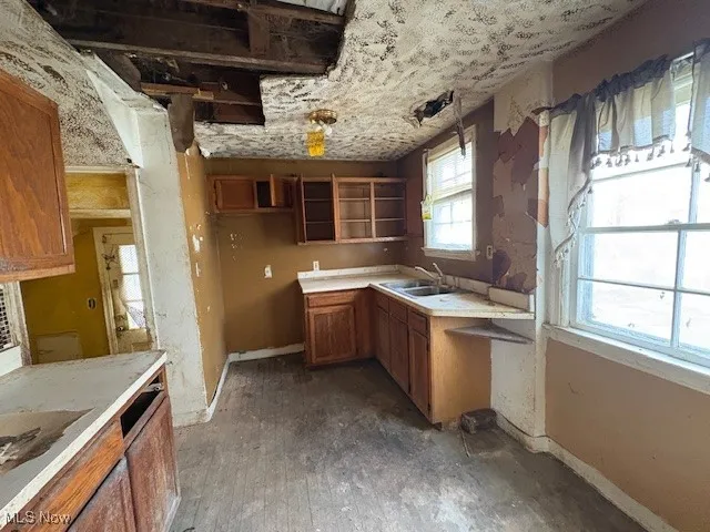 Kitchen featuring brown cabinetry, light countertops, and open shelves