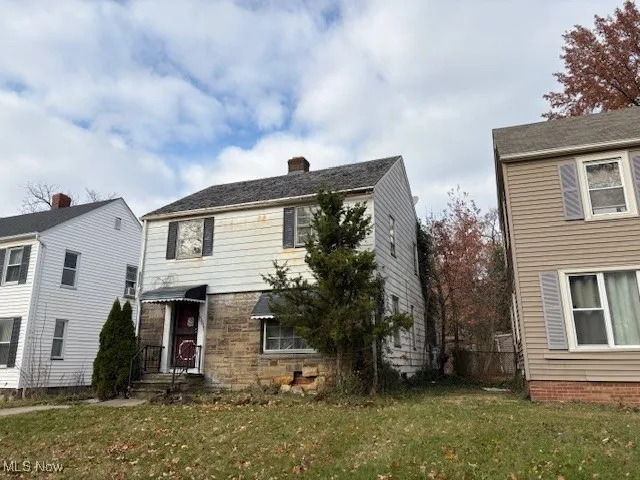 View of front of home featuring a front lawn, stone siding, and a chimney