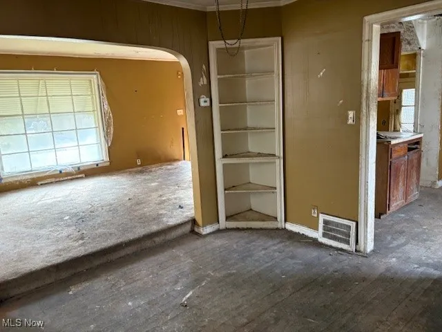 Unfurnished dining area with arched walkways and ornamental molding