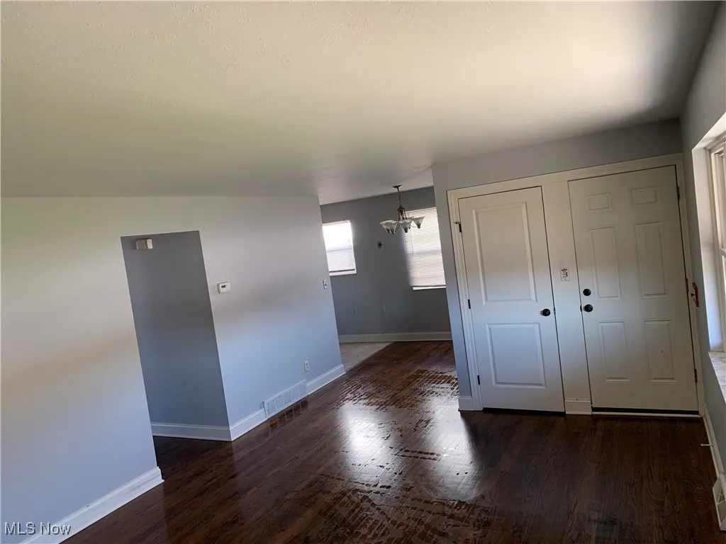 Unfurnished room featuring a chandelier and dark wood-type flooring