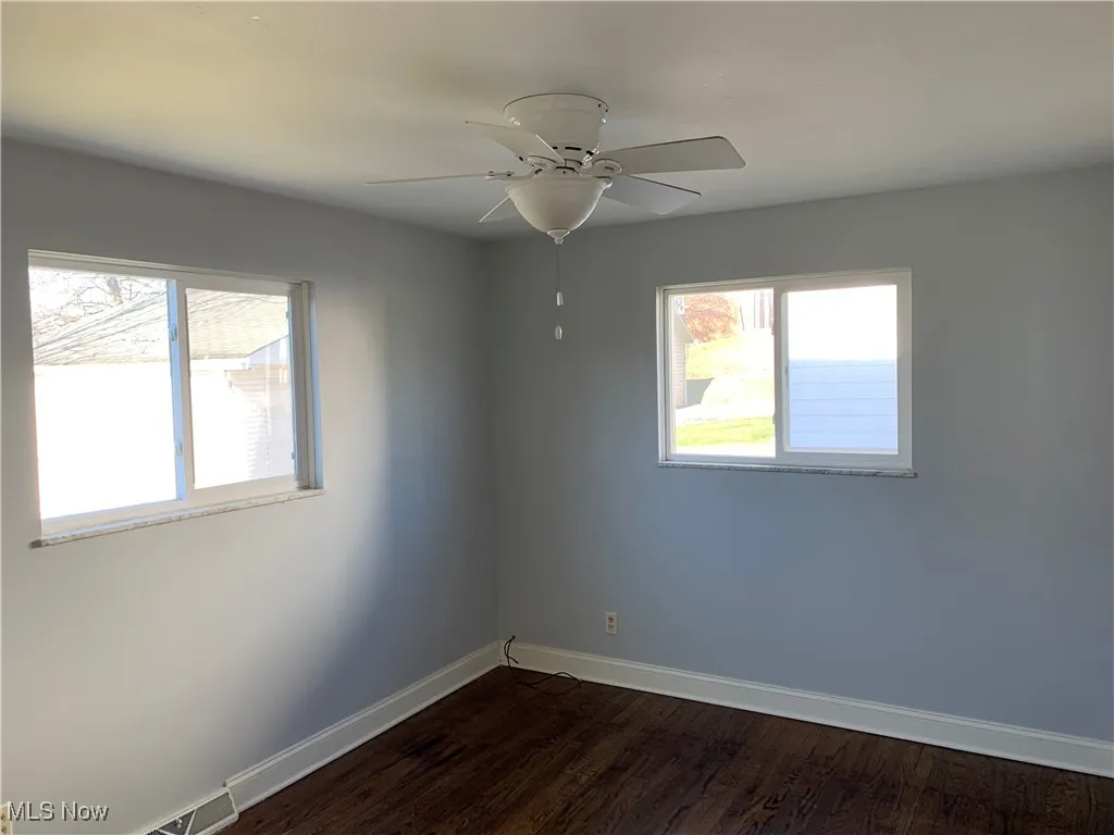 Unfurnished room featuring dark wood-style floors and a ceiling fan