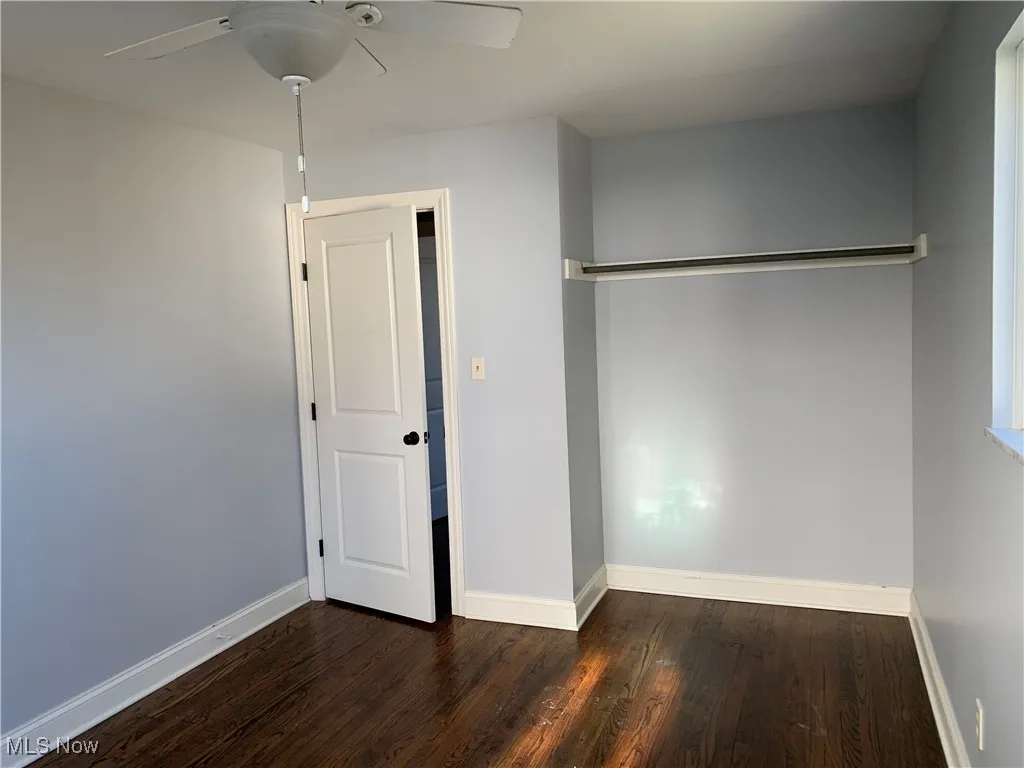 Unfurnished bedroom featuring dark wood-type flooring and a ceiling fan