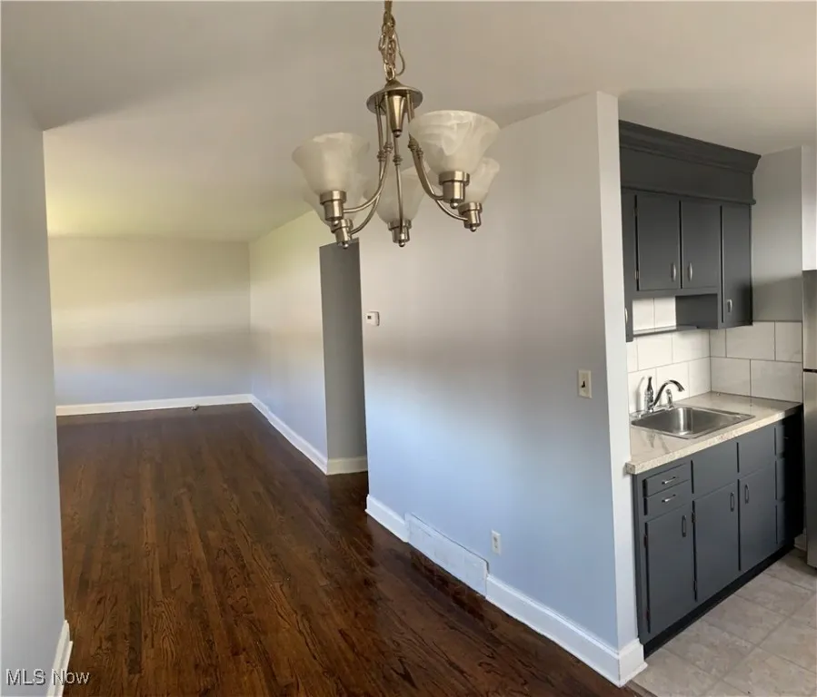 Unfurnished dining area with a chandelier and dark wood-type flooring