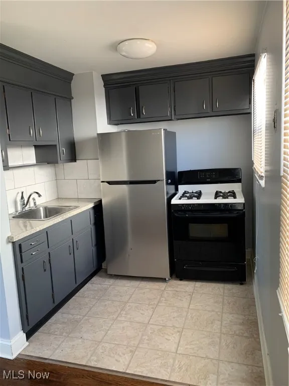 Kitchen featuring appliances with stainless steel finishes, light countertops, gray cabinetry, and tasteful backsplash