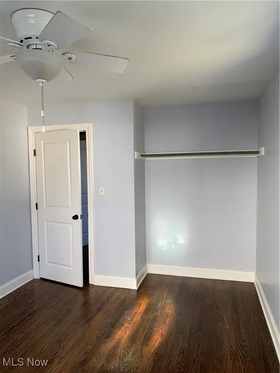 Unfurnished bedroom featuring dark wood-style floors and a ceiling fan