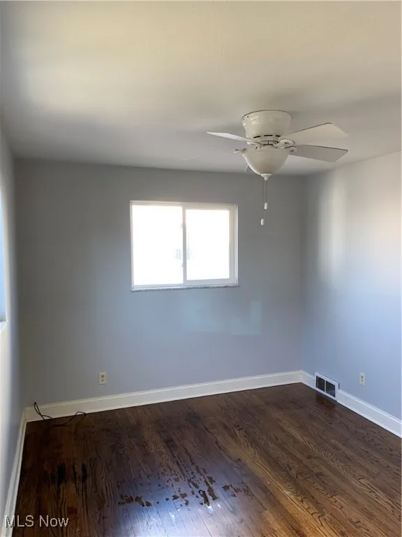 Unfurnished room featuring dark wood finished floors and a ceiling fan