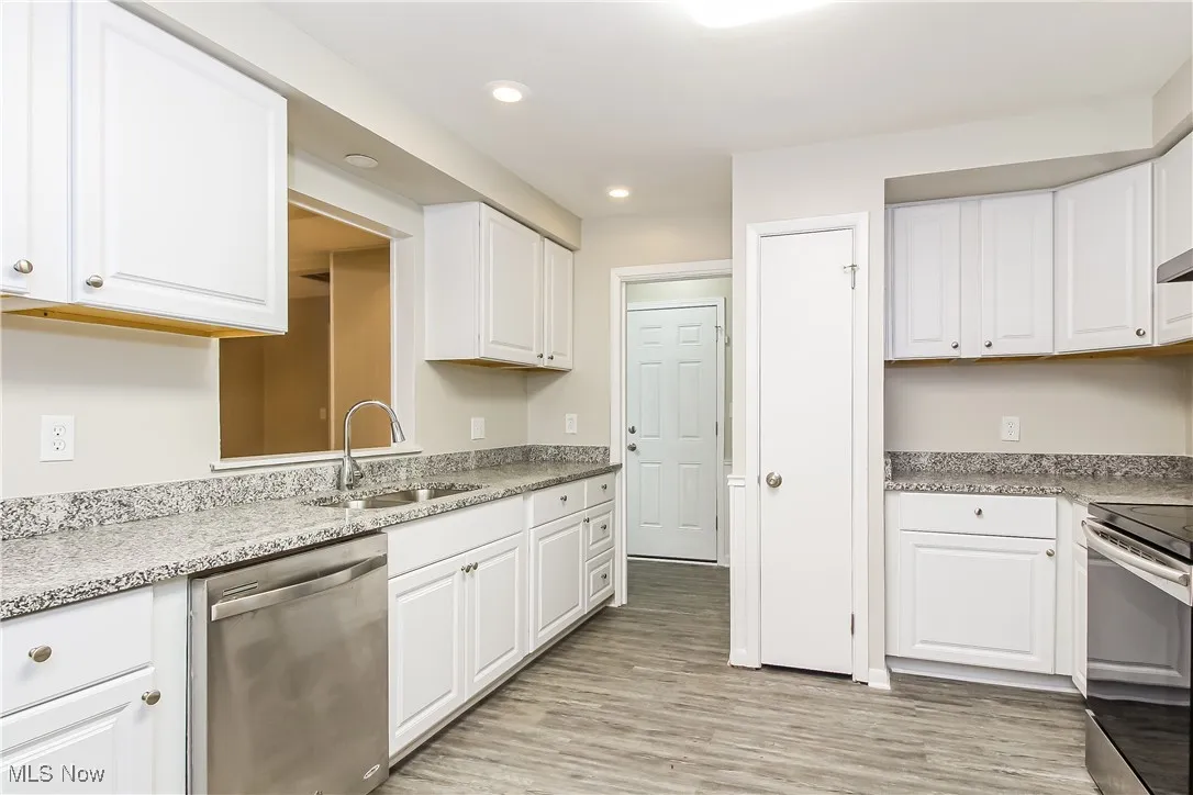 Kitchen with stainless steel appliances, recessed lighting, light wood-style floors, and white cabinets