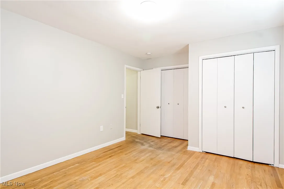 Unfurnished bedroom with light wood-style floors and two closets