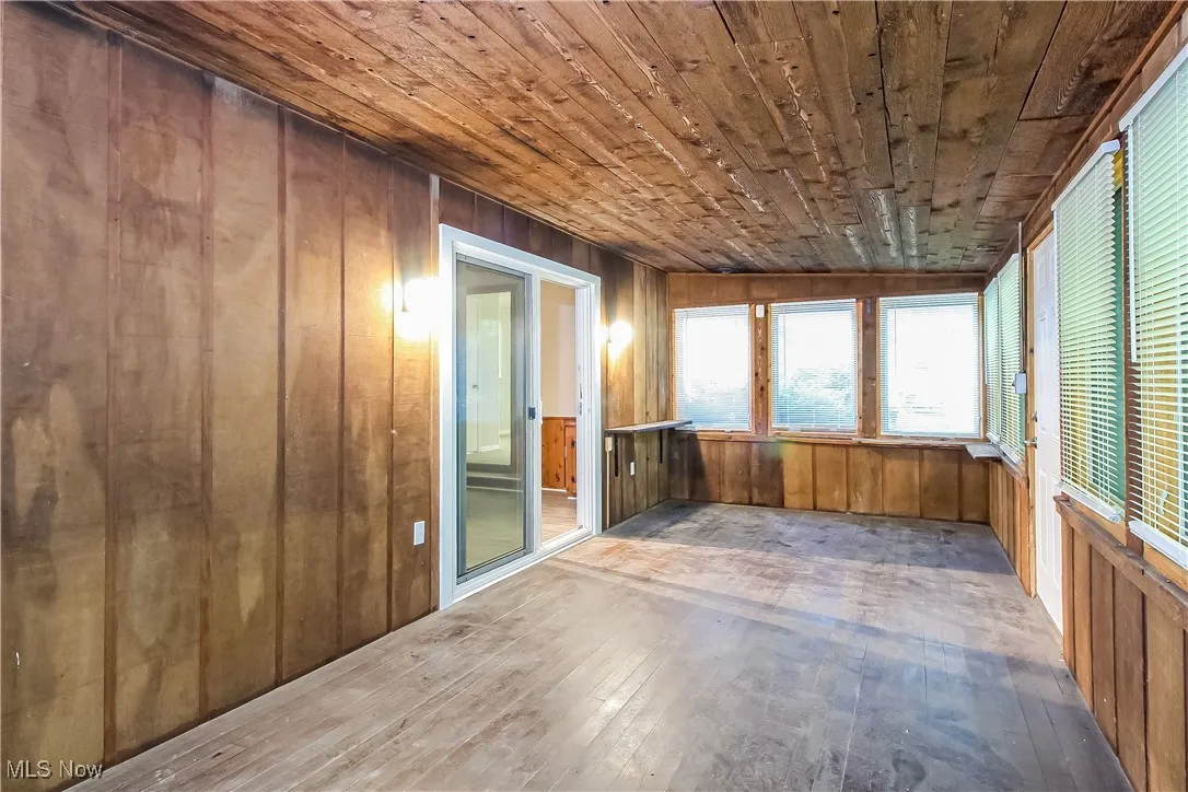 Unfurnished sunroom featuring wooden walls, hardwood / wood-style flooring, and wooden ceiling