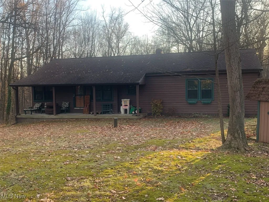 Rear view of house featuring a shingled roof, a yard, and covered porch