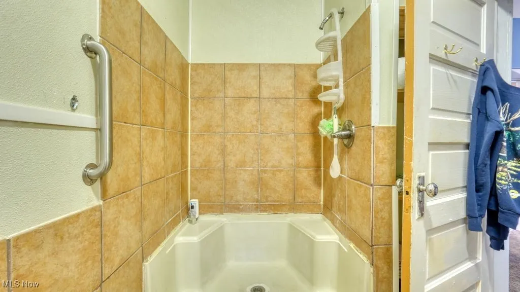 Bathroom with a shower and a textured wall