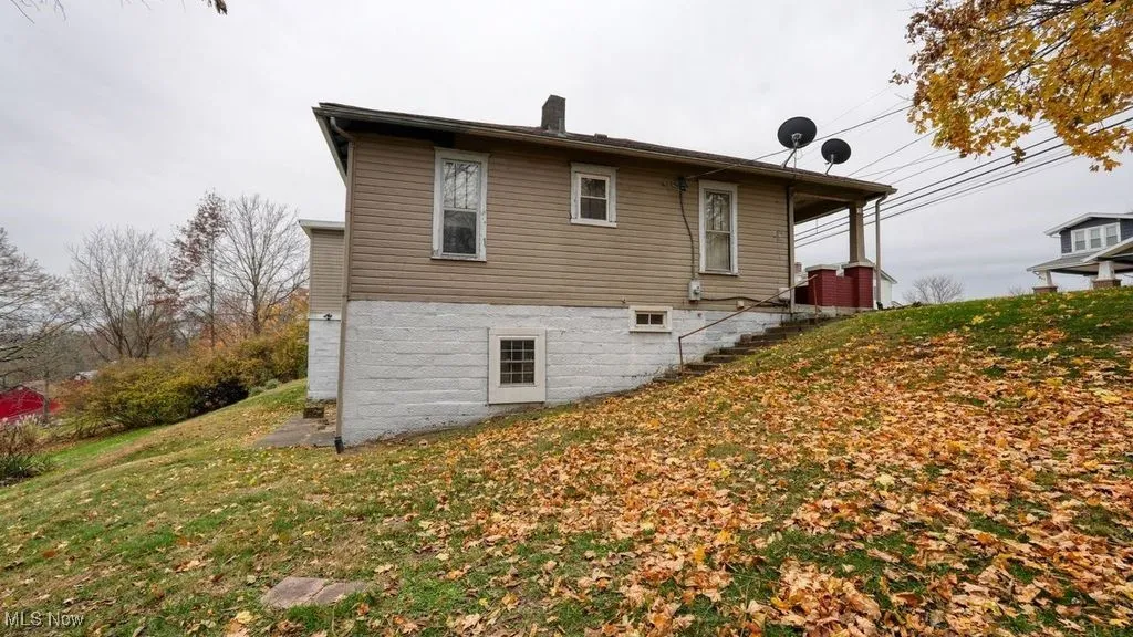 Rear view of property featuring a chimney and a lawn