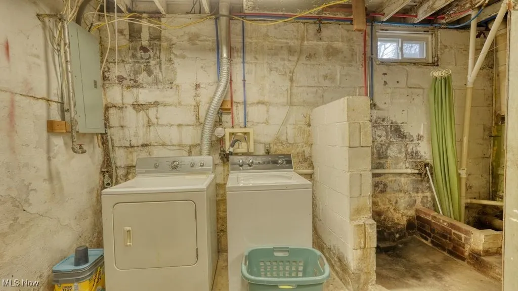 Laundry area with washing machine and dryer, concrete flooring, and electric panel
