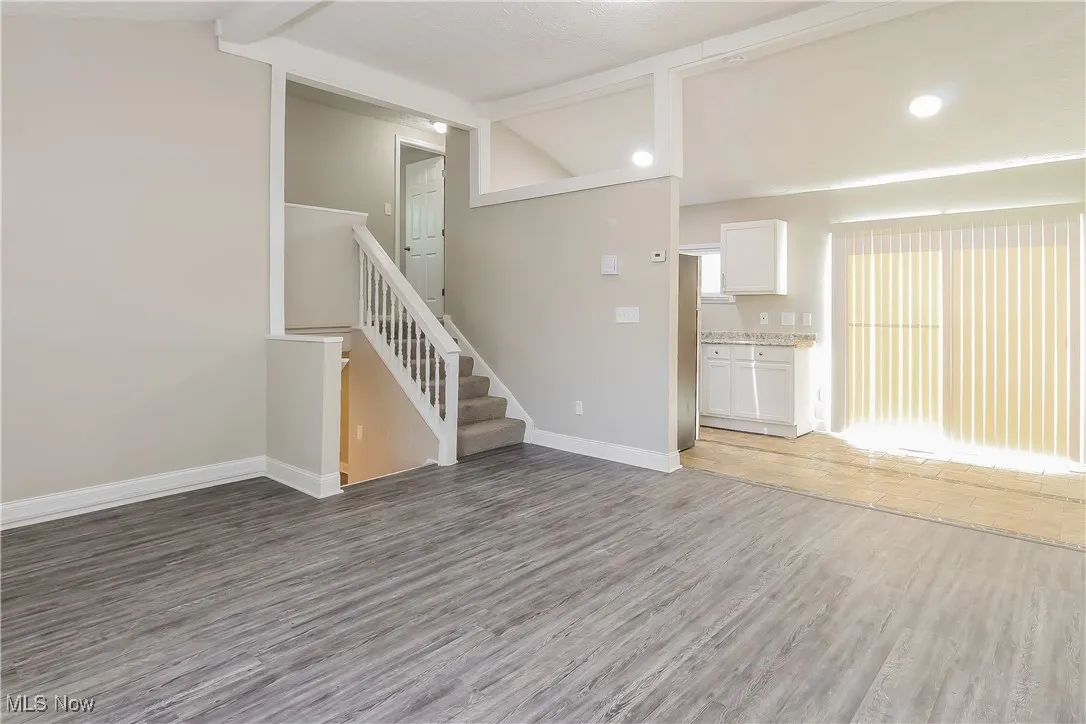 Unfurnished living room with light wood finished floors and stairway