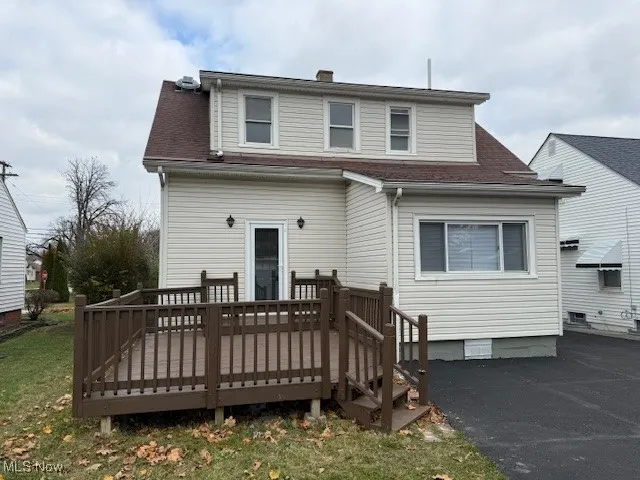 Back of property with a deck, roof with shingles, a chimney, and a yard