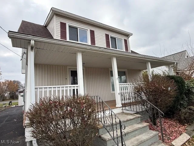 Farmhouse featuring covered porch and a shingled roof