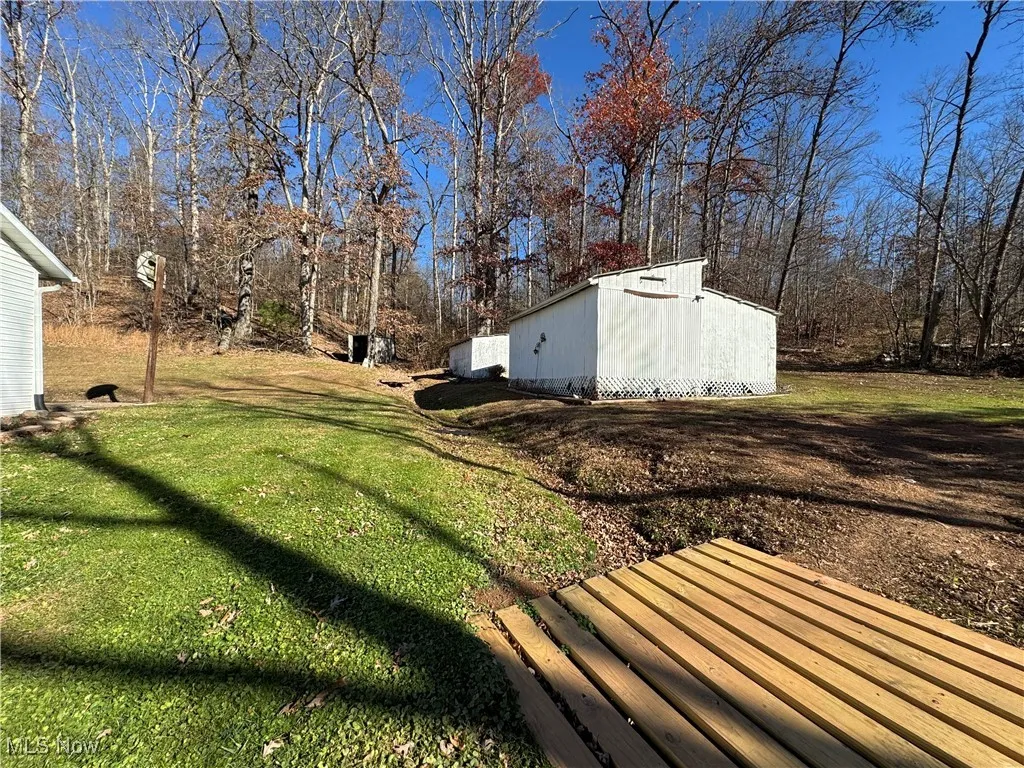 View of green lawn with an outbuilding and view of wooded area