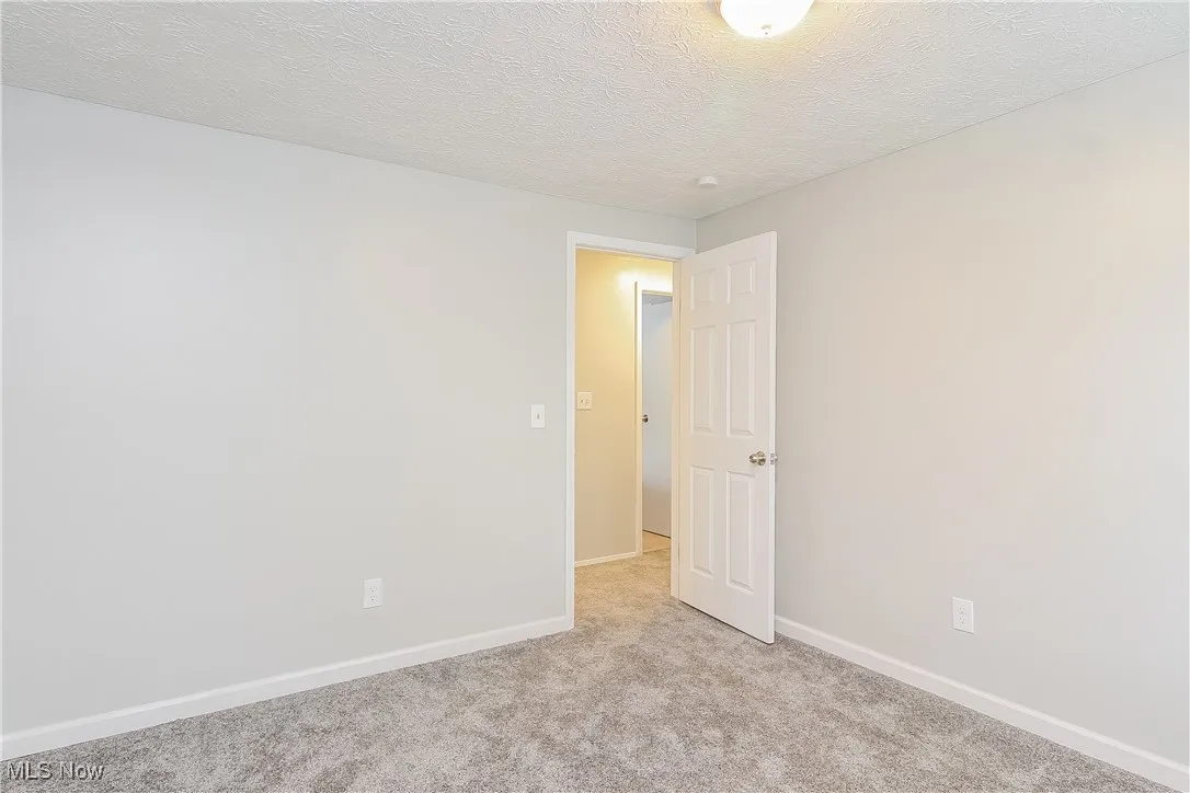 Spare room with a textured ceiling and light colored carpet