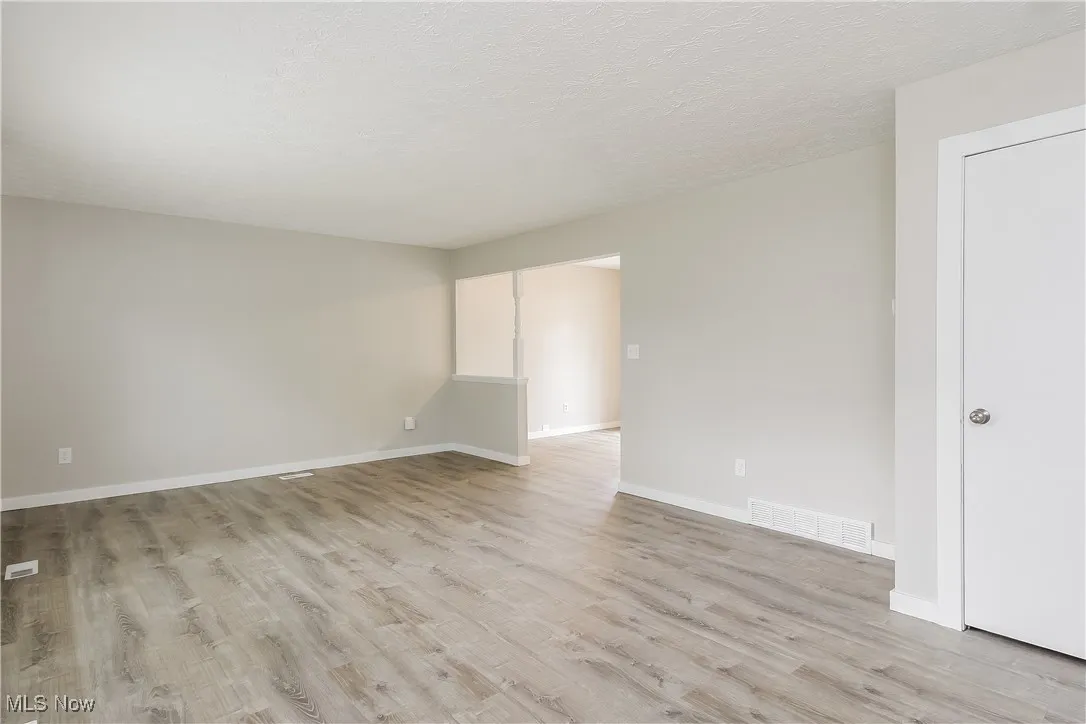 Unfurnished room with light wood-type flooring and a textured ceiling