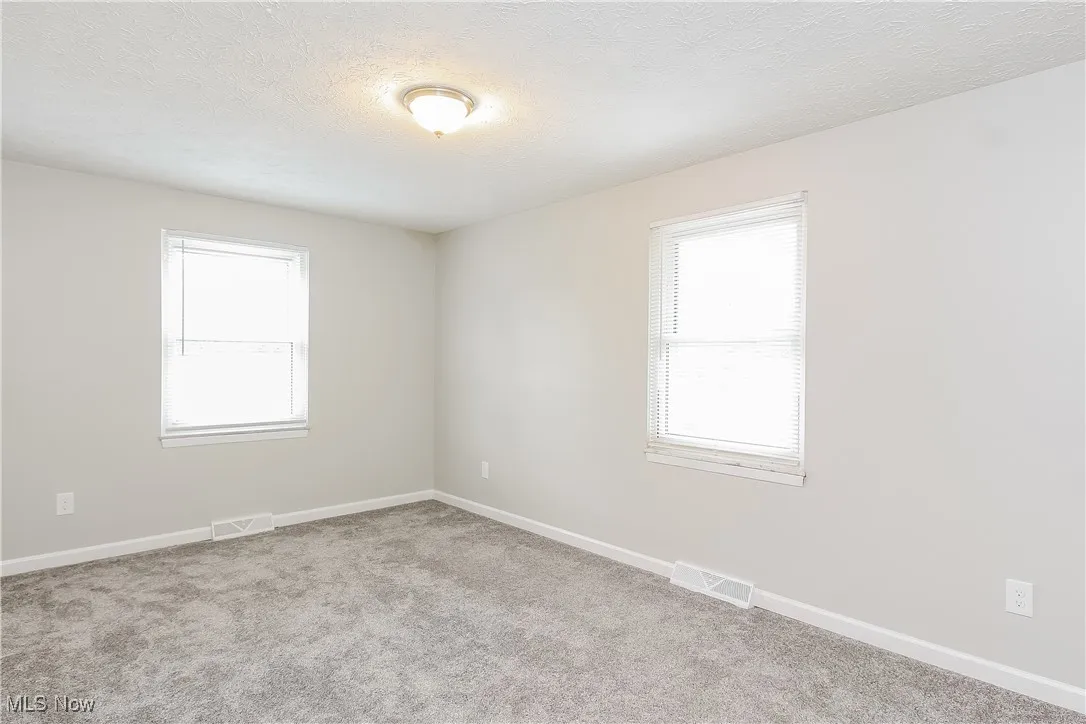 Spare room featuring light colored carpet and a textured ceiling