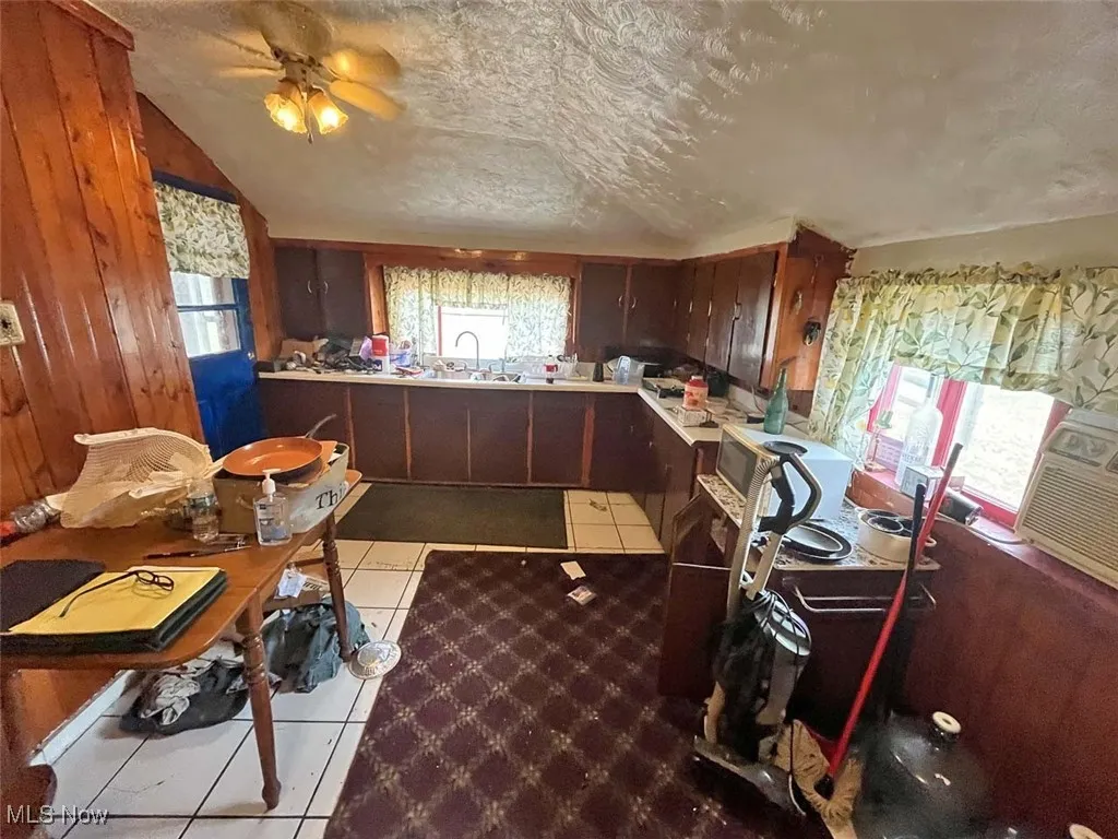Kitchen with lofted ceiling, a textured ceiling, light countertops, light tile patterned floors, and dark brown cabinetry