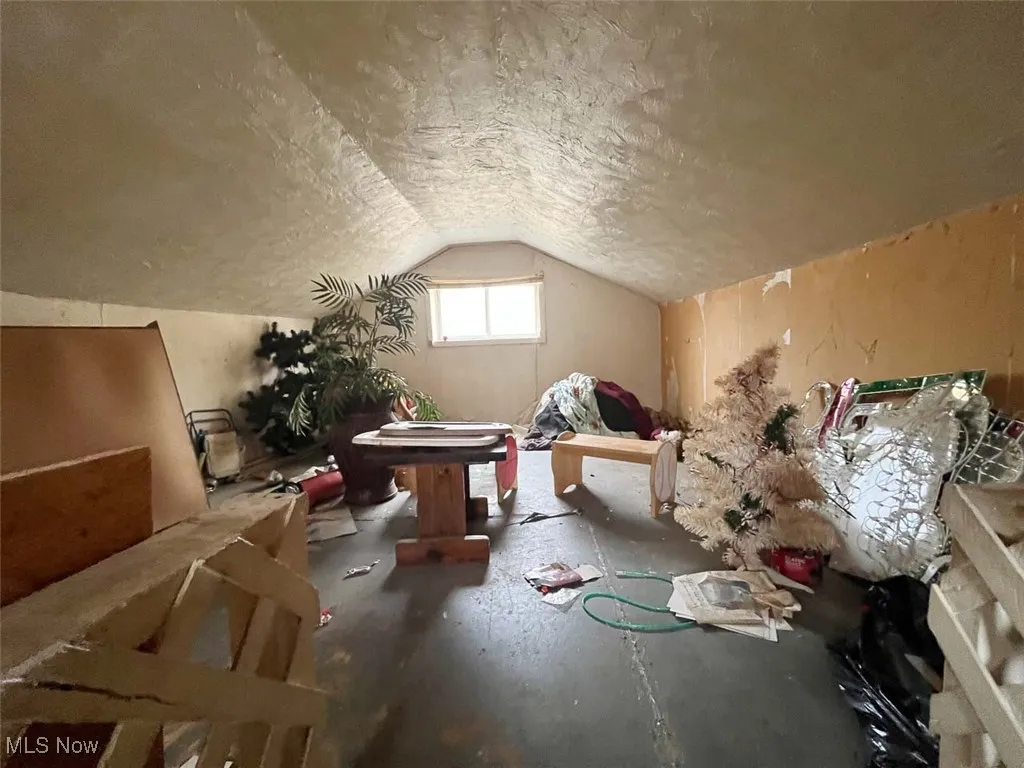 Additional living space featuring vaulted ceiling and a textured ceiling