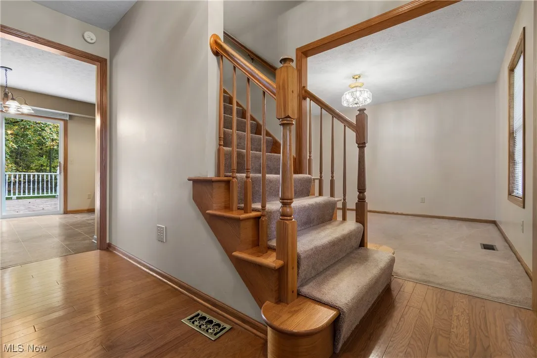 Stairway featuring a chandelier, healthy amount of natural light, hardwood / wood-style floors, and a textured ceiling