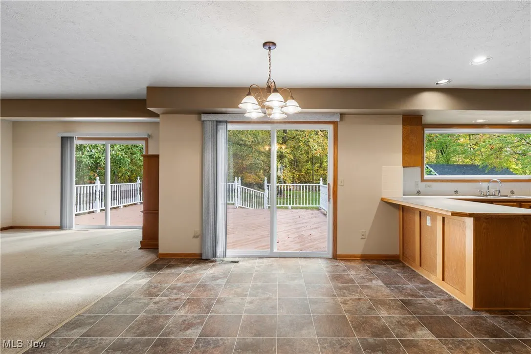 Unfurnished dining area featuring a chandelier, stone finish floors, a textured ceiling, and recessed lighting