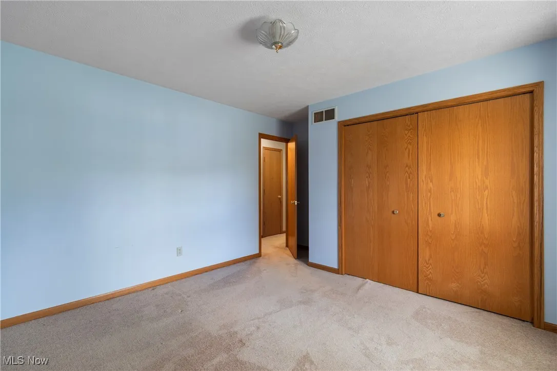 Unfurnished bedroom featuring light carpet and a closet