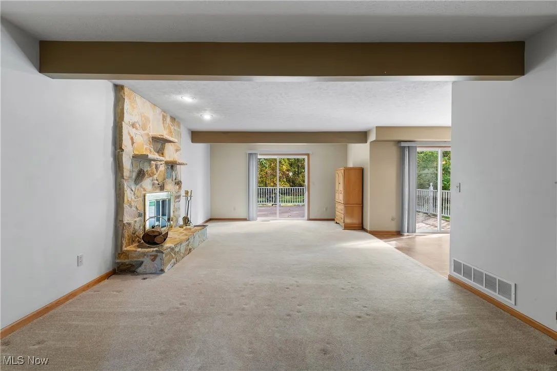 Unfurnished living room featuring carpet, a fireplace, and a textured ceiling