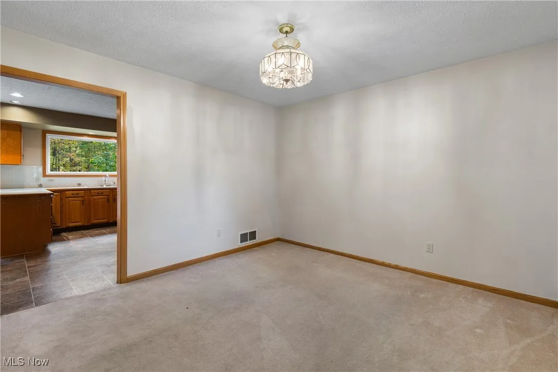 Spare room featuring carpet floors, a textured ceiling, and a chandelier