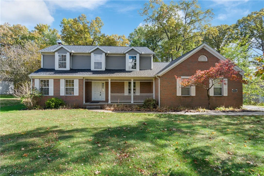 Traditional-style home with covered porch, a front lawn, and brick siding