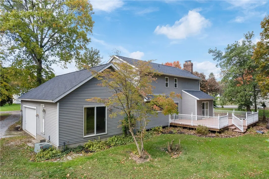 Back of property featuring a lawn, a chimney, a deck, and a shingled roof