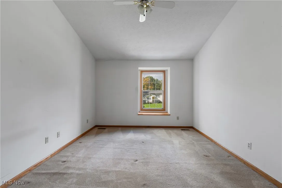 Spare room with a textured ceiling, light carpet, and ceiling fan
