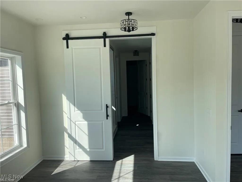 Spare room with a barn door and dark wood-style floors