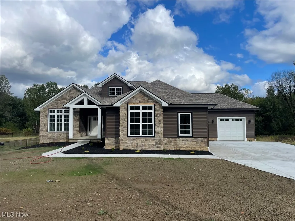 Craftsman-style home with a shingled roof, an attached garage, stone siding, and concrete driveway