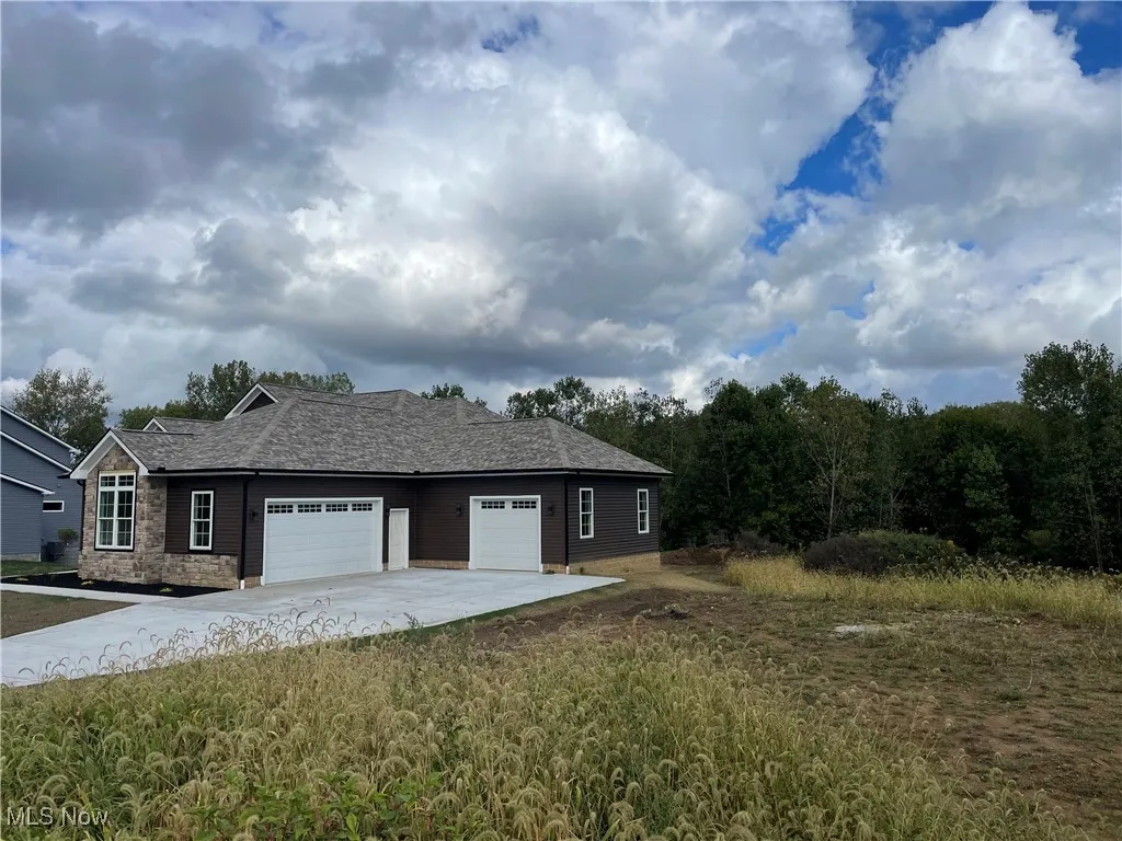 View of property exterior featuring concrete driveway, a garage, and roof with shingles