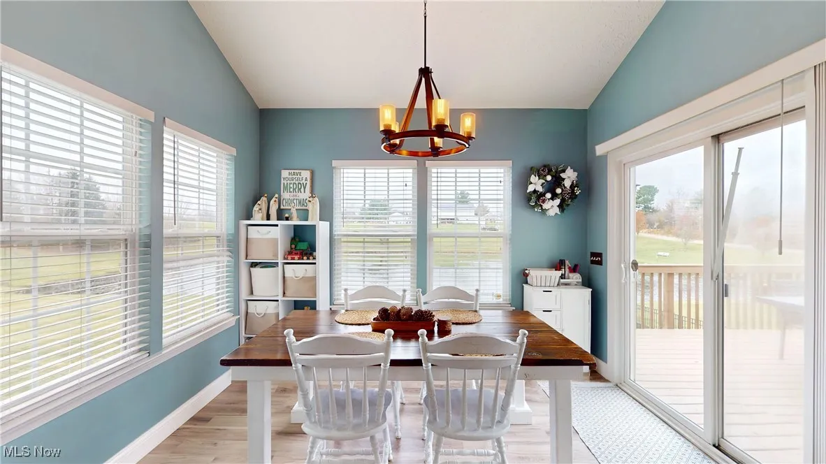 Dining space featuring light wood-style flooring, a chandelier, and lofted ceiling