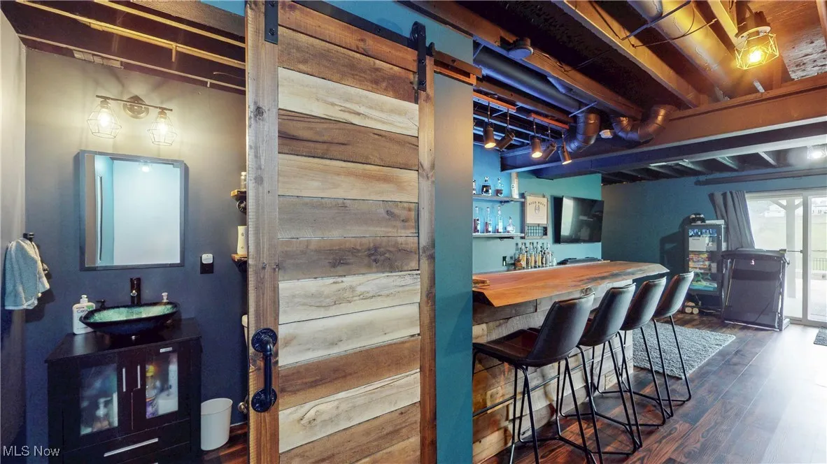 Indoor dry bar featuring dark wood-type flooring, a barn door, and butcher block countertops