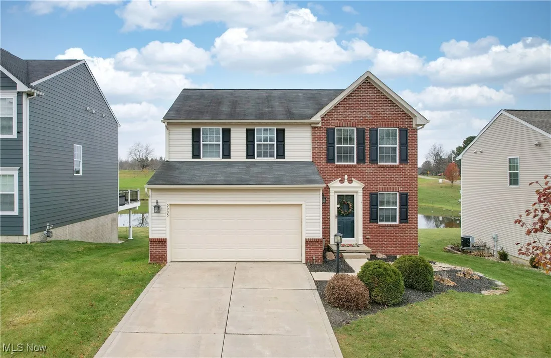 View of front of property with a garage, driveway, a front yard, and a water view