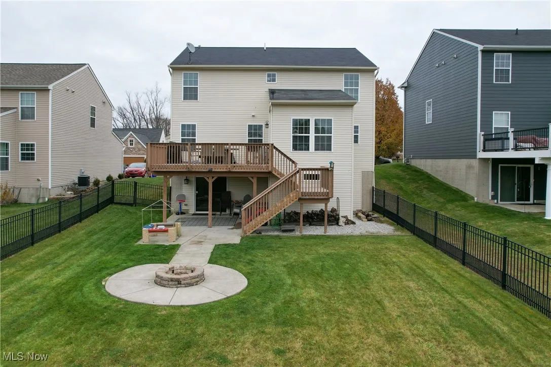 Back of property with a patio, a fire pit, stairs, a wooden deck, and a fenced backyard