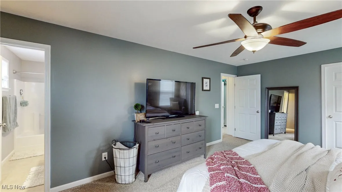 Bedroom featuring light colored carpet, ceiling fan, and ensuite bathroom