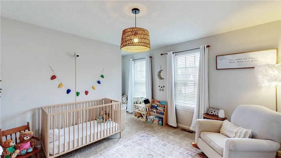 Carpeted bedroom with a crib and baseboards