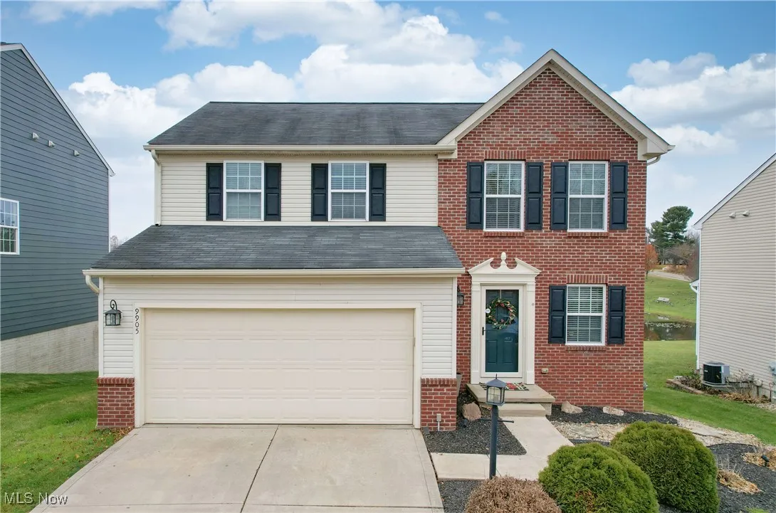 View of front of home with driveway, a garage, brick siding, and a front lawn